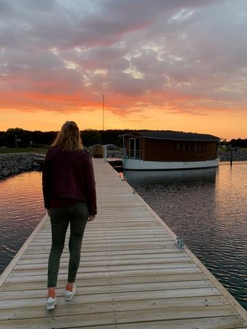 Kvinde på badebro mod solnedgangen