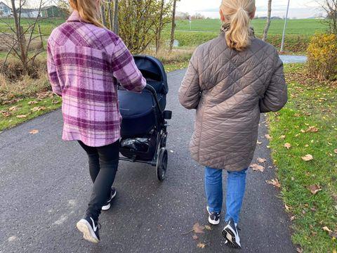 Vänner går på promenad med barnvagn tillsammans